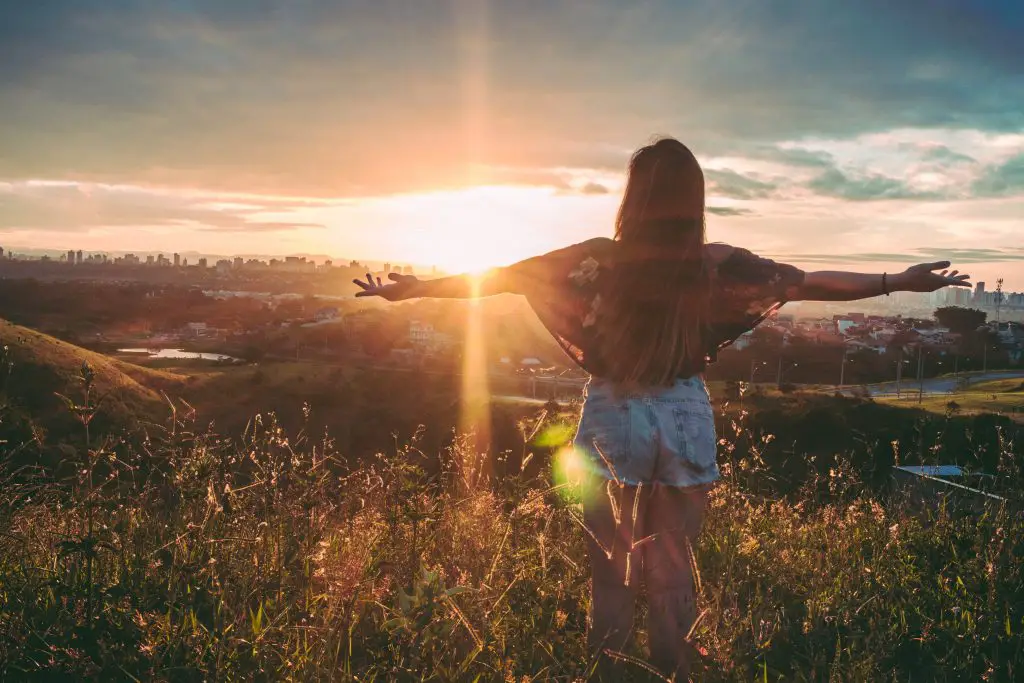 a girl spreading her hands towards the sunrise for the article 9 steps to financial freedom