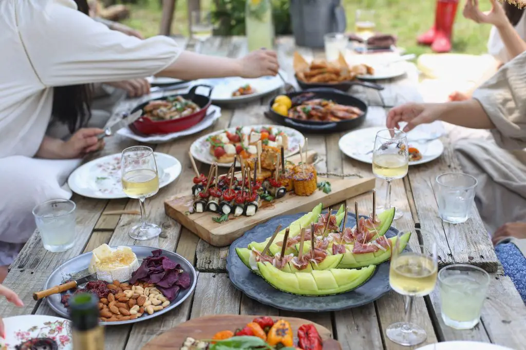 how to organize a potluck dinner? Here is a picture of people enjoying different food in the table