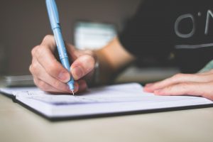 how to plan a potluck dinner, a picture of a person writing in a notebook