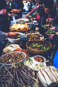 how to organize a potluck dinner. A picture of people enjoying lots of food in the table